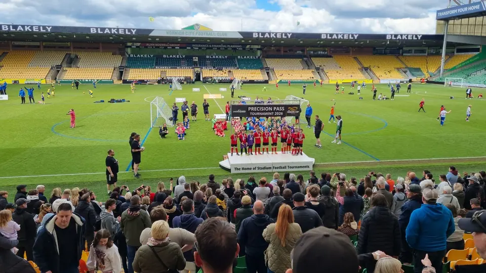 Precision Pass tournament ceremony on the pitch at Carrow Road, with players and spectators in the stands